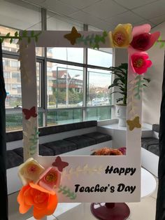 a happy teacher's day card with flowers and butterflies on the front, sitting in an office window sill