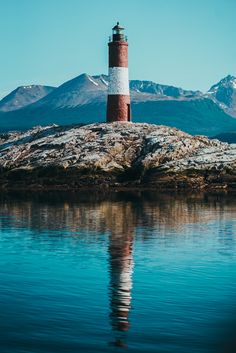 a light house sitting on top of a small island in the middle of some water