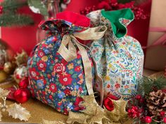 two christmas bags sitting on top of a table next to pine cones and other holiday decorations