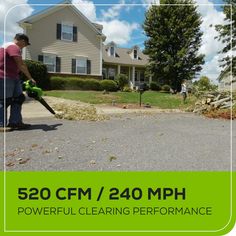 a man is using a leaf blower to clean the street in front of his house