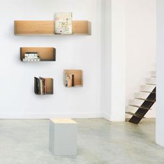 three shelves with books on them in a white room next to a stair case and bookcase