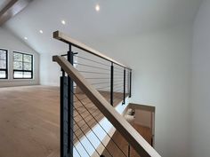 an empty room with wood flooring and metal handrails on the second story