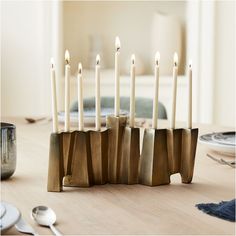 a group of candles sitting on top of a wooden table next to plates and utensils