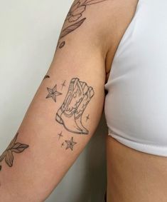 a woman's arm with tattoos on it and a cowboy boot in the middle