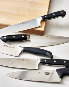 three knives are sitting next to each other on a cutting board