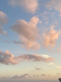 the airplane is flying high in the sky above the beach and water at sunset or dawn