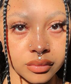 a close up of a person with braids on her nose and nose piercing in front of the camera