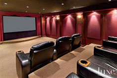 a home theater with black leather chairs and red curtains