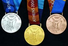 three olympic medals are displayed on a black surface with blue, yellow and red ribbons