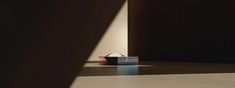 an empty basket sitting on top of a floor next to a wall with light coming through it