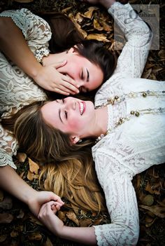 two women laying on the ground with their arms around each other