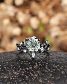 a diamond ring sitting on top of a black piece of rock in front of some rocks