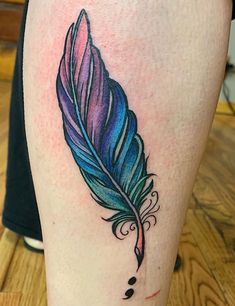 a colorful feather tattoo on the leg