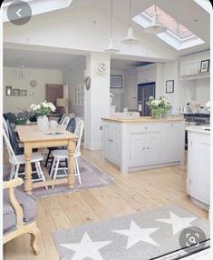 an open kitchen and dining area with white cabinets, stars rugs on the floor