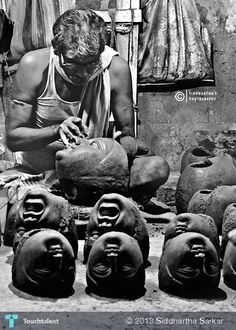 black and white photograph of a man working on clay pots in front of other pottery