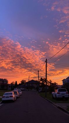 cars are parked on the side of the road as the sun sets in the background