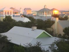 the sun is setting over some houses and trees