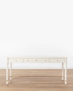 a white table sitting on top of a hard wood floor next to a white wall