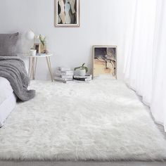 a bedroom with white fur rugs on the floor and pictures hanging on the wall