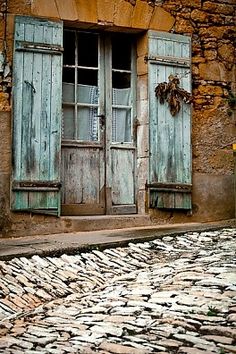 an old stone building with shutters open