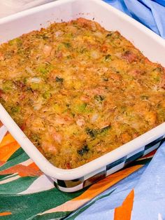 a casserole dish with broccoli and meat in it on a colorful cloth