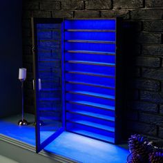 a blue lighted display case in front of a brick wall next to a candle holder