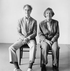 an old black and white photo of two people sitting next to each other on chairs