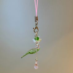 a pink cord is attached to a charm with flowers and leaves hanging from it's end