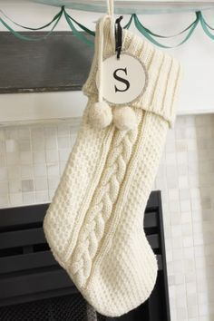 a white christmas stocking hanging from a mantel with a monogrammed s on it