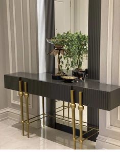 a black and gold console table with a potted plant on it in front of a mirror