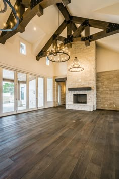 an empty living room with wood floors and chandelier hanging from the ceiling,