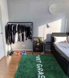 a bed room with a neatly made bed next to a green rug on the floor