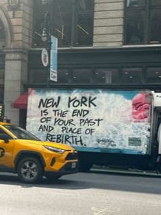 a yellow truck parked on the side of a road next to a tall building with graffiti written on it