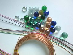 several different colored beads and wires on a white surface