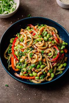 a blue bowl filled with noodles and vegetables