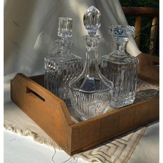 three glass decanters in a wooden tray on a table