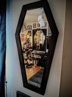 a mirror hanging on the side of a wall next to a christmas tree