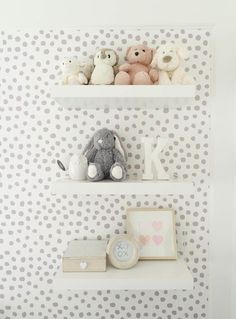 two white shelves with teddy bears on them and a clock in front of the wall