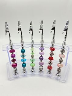 several different colored beads are in a clear holder with silver handles and metal tips on each side