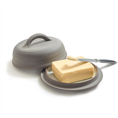 a piece of butter sitting on top of a plate next to a knife and container