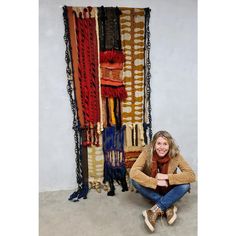 a woman sitting on the floor in front of an art piece with chains hanging from it