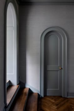 an open door in the corner of a room next to a wooden floor and stairs