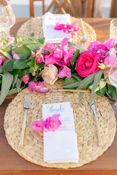 a place setting with pink flowers and greenery