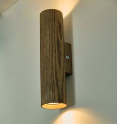 a wooden light fixture mounted to the side of a white wall with two lights on it