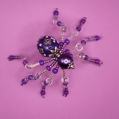 a purple beaded spider brooch on a pink background