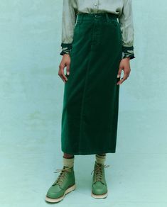 A person modeling an ensemble featuring THE GREAT. HOL 24's The Velvet Column Skirt in Emerald, paired with a green button-up shirt, green boots, and cream socks, stands against a green background highlighting women's fashion. Denim Sweater Jacket, Female Friendship, Column Skirt, Red Wing Shoes, Denim Sweater, The Velvet, Sweater Sale, A Bar, Top Sales