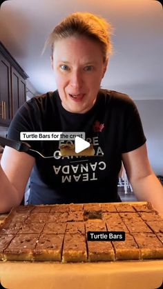 a woman holding a knife in front of a tray of brownies