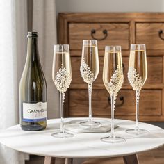 three champagne flutes and four wine glasses sitting on a table next to an empty bottle