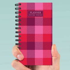 a hand holding a pink and red plaid planner