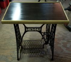 an antique singer sewing table with black and gold top